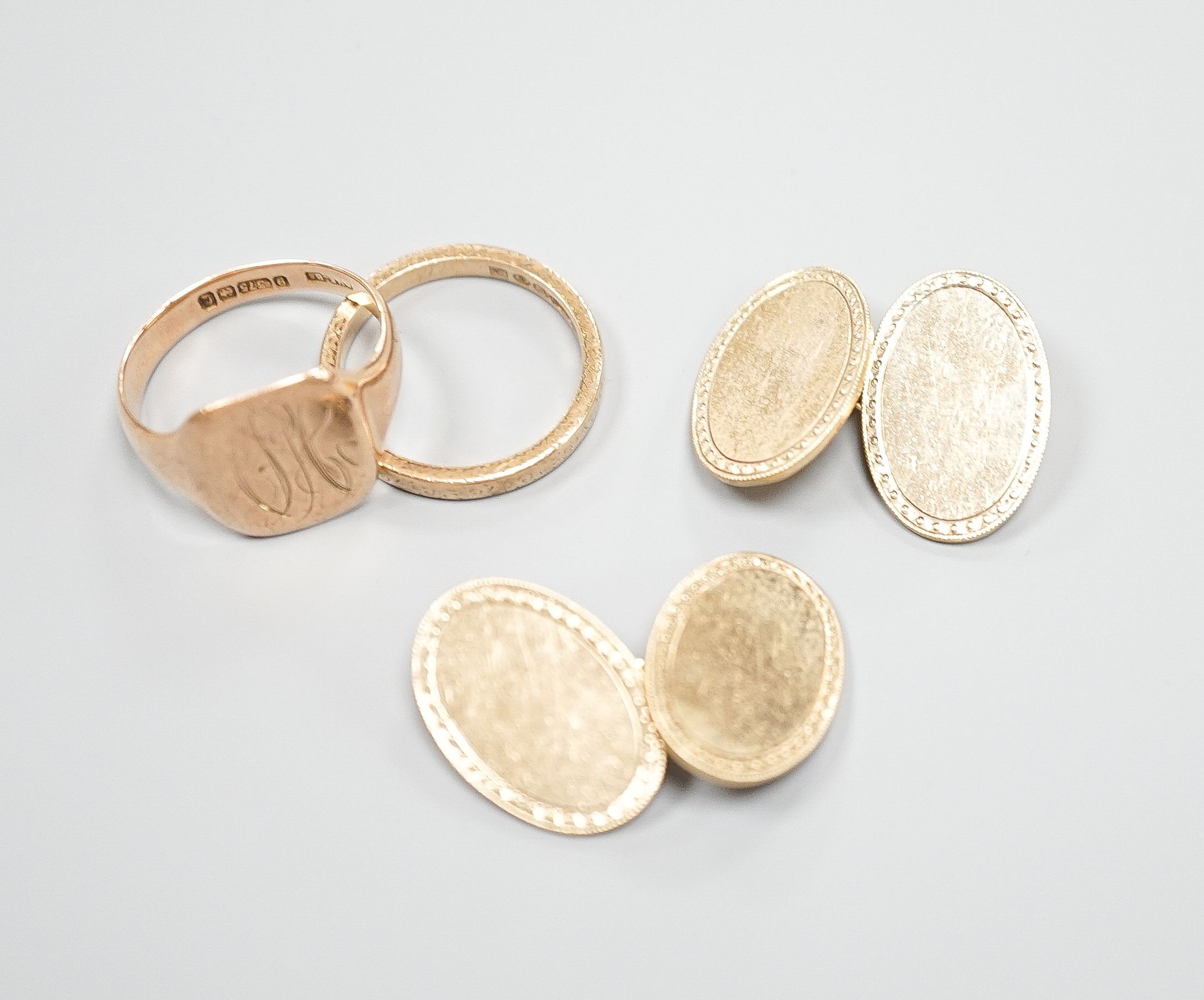 A 9ct gold wedding band, a 9ct gold signet ring and a pair of 9ct gold oval cufflinks